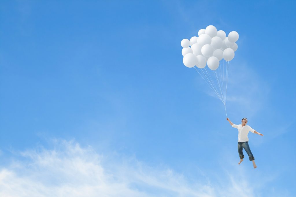 Photo d'un monsieur qui vole avec des ballons dans la main